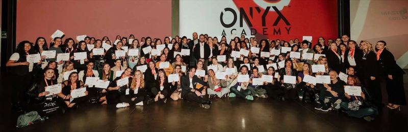 Foto di gruppo di decine di diplomate ONYX con l'attestato in mano, sotto il logo ONYX Academy