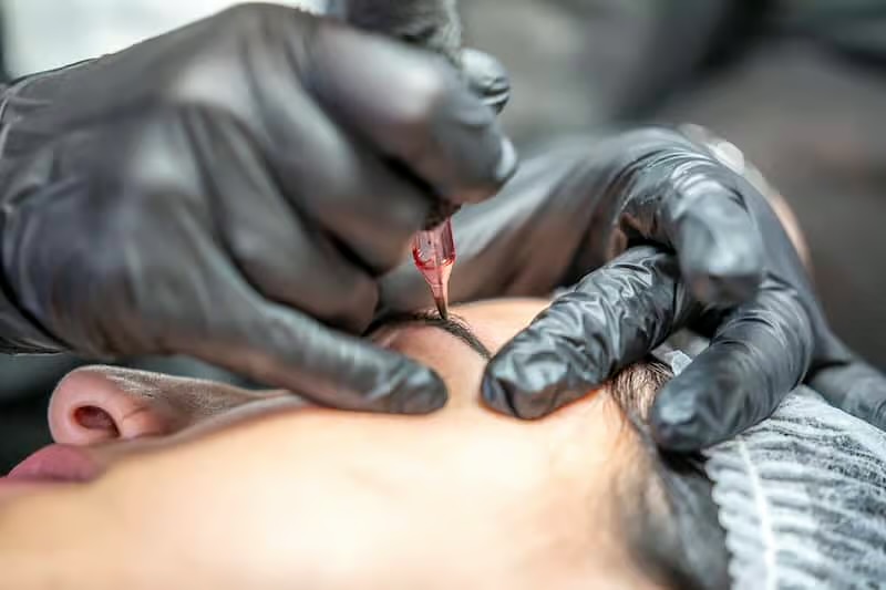 Mani con i guanti neri che pigmentano il sopracciglio con il dermografo