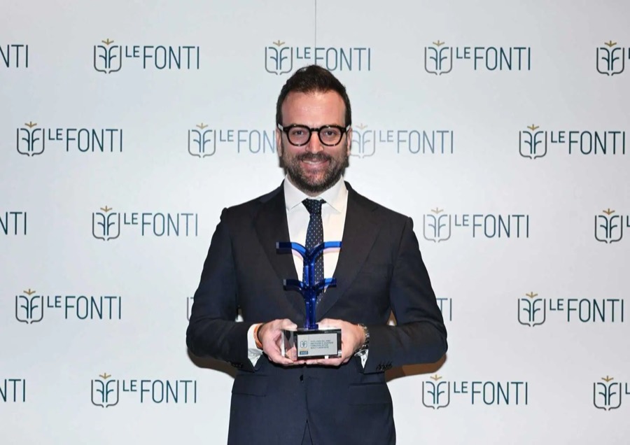 Daniele Salamina con il trofeo Le Fonti Awards 2025 davanti al pannello del premio