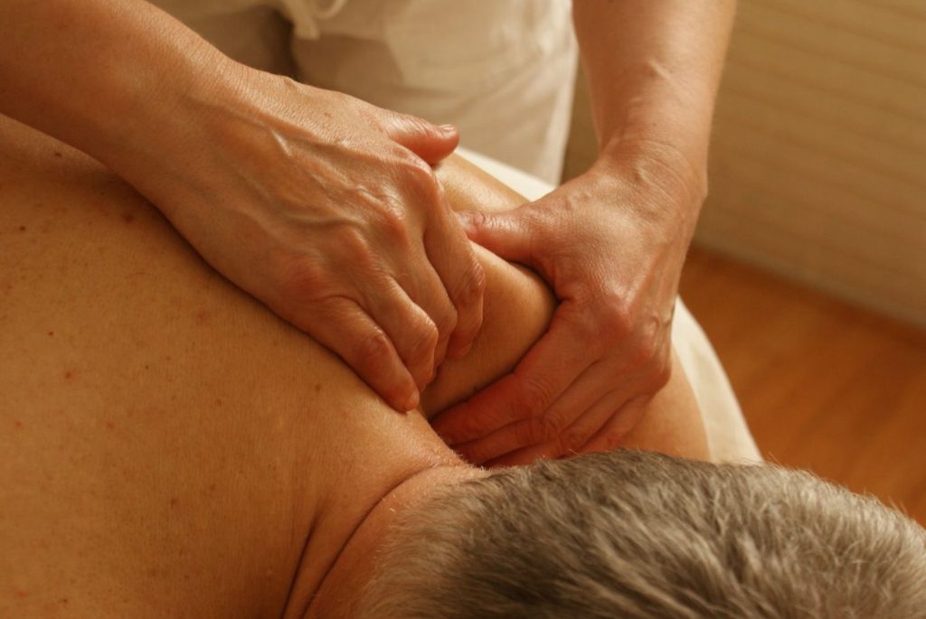 Massaggiatore sportivo del benessere che tratta collo e spalle